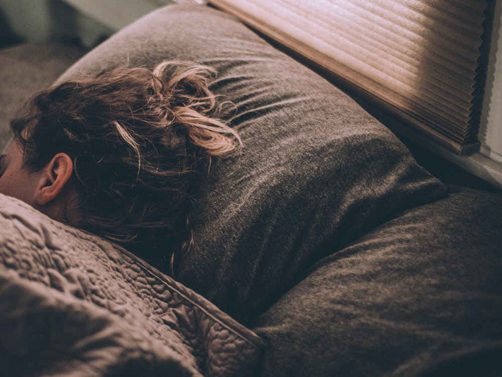 Iemand die uitgeput in bed ligt bij het ochtendlicht